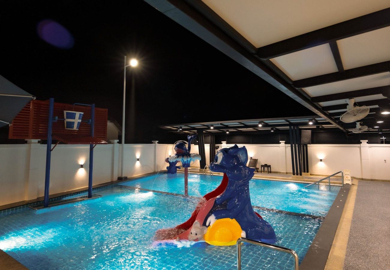 Night view of private swimming pool with water slide and basketball hoop at Le's Homestay Lot 916